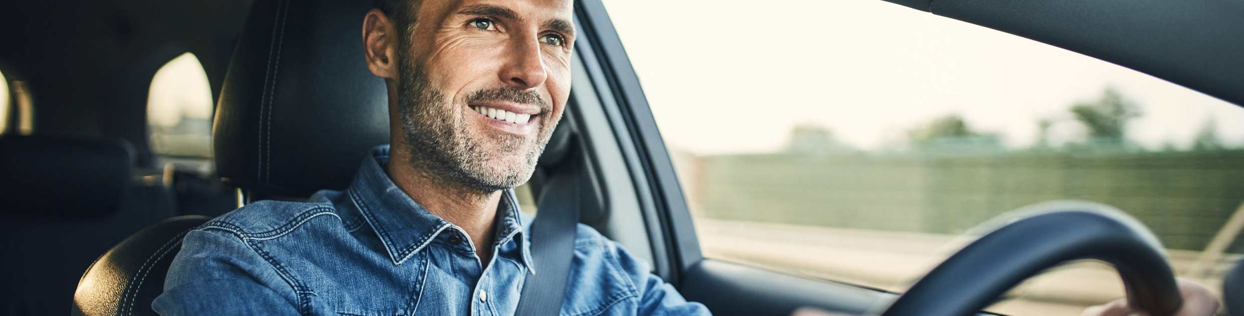 Homme souriant au volant d'une voiture