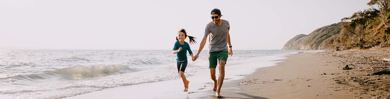 Père courant sur la plage avec sa fille