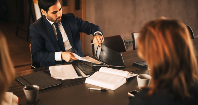 Homme assis à un bureau sortant des documents de sa mallette