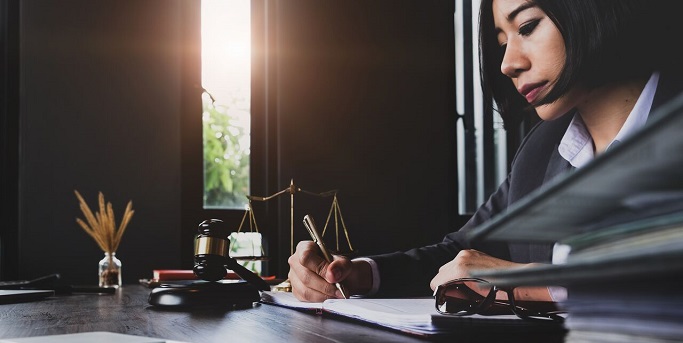 ALM Femme examinant des documents à son bureau 683x343