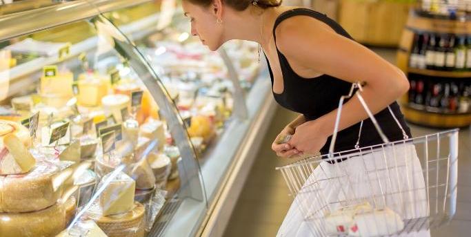 1280 Web Consommatrice observant la vitrine réfrigérée des fromages dans un supermarché