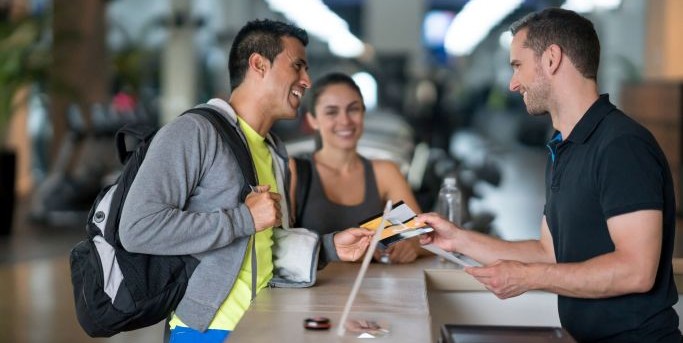 Homme discutant avec le réceptionniste d'une salle de sport