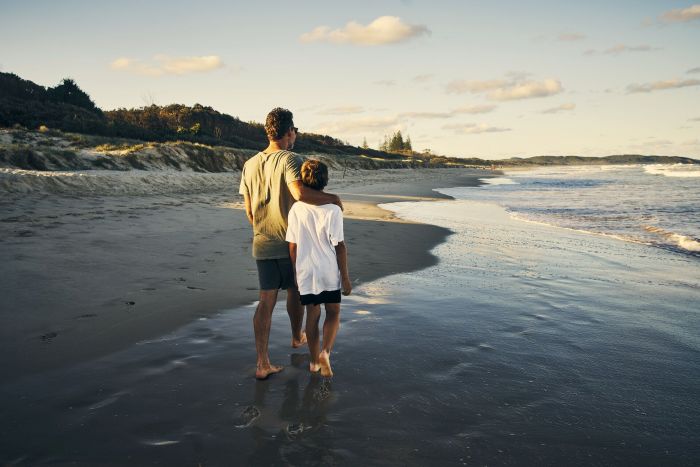 Un père et son fils qui marchent le long de la plage