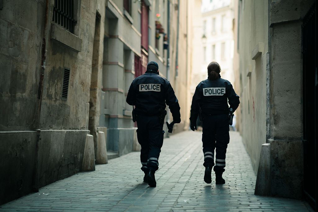 Deux agents de police en train de marcher dans une rue étroite